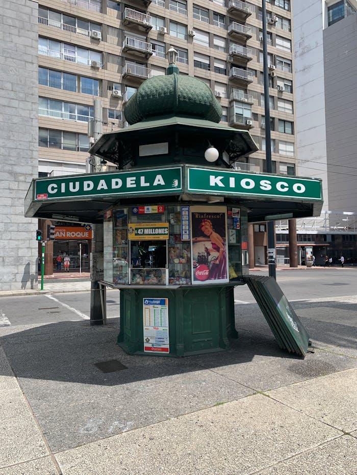 Public kiosk in an urban setting surrounded by high-rise buildings, offering local goods.